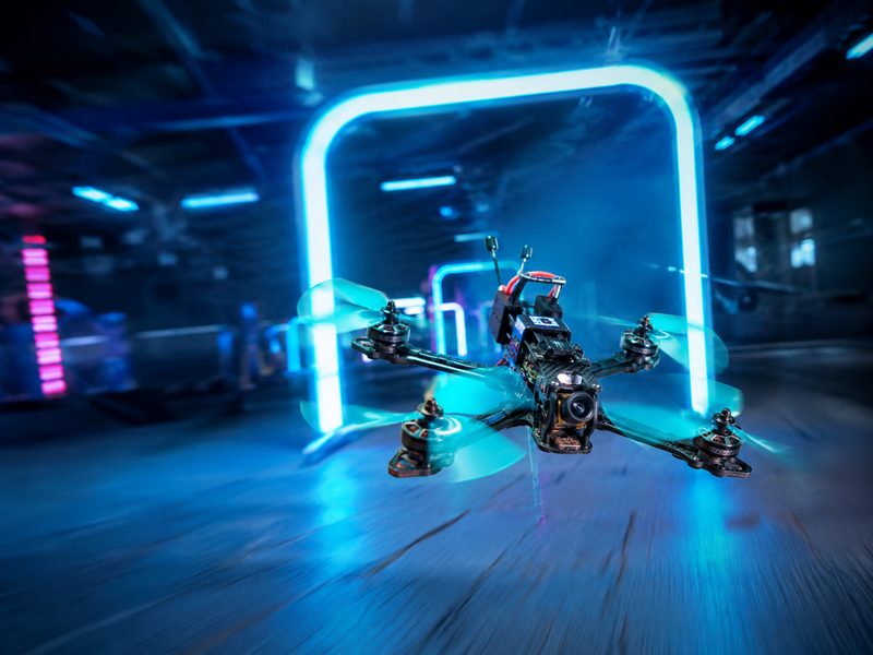 Racing drone flying through neon-lit gate